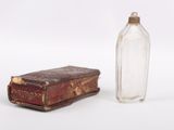 a small glass bottle next to a book on a table