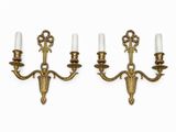 a pair of brass sconces with white candles on them
