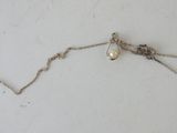 a close up of a necklace on a white surface with a chain
