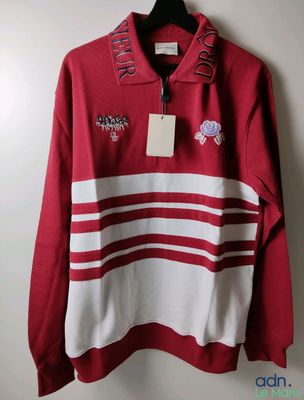 a red and white sweater hanging on a hanger on a wall