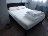 a bed with white sheets on it in a small room