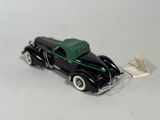 a black toy car with a green top on a white surface