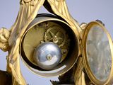 a gold clock with a silver ball in the middle of it