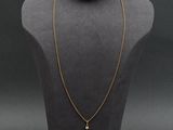 a gold necklace with a cross on a mannequin head