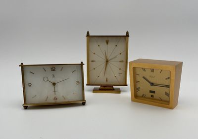 trois horloges de tailles différentes posées les unes à côté des autres sur une surface blanche