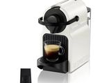 a white coffee machine with a cup of coffee next to it