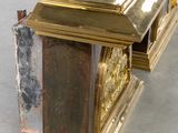 a gold clock sitting on top of a wooden table