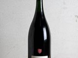 une bouteille de vin posée sur une table à côté d'un verre de vin