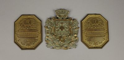 trois médailles d'or représentant des armoiries sur fond blanc