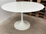a white table with a round base in a warehouse