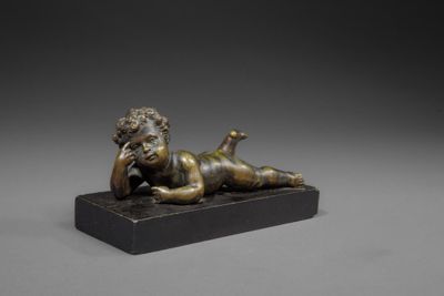 a bronze figurine of a boy laying on his stomach