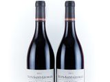 two bottles of red wine sitting next to each other on a white surface