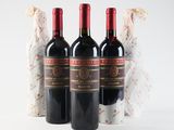 three bottles of red wine sitting next to each other on a white surface