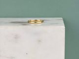 une photo d'une bague en or posée sur un bloc de marbre blanc