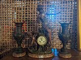 statue représentant une femme avec une horloge et deux vases posés sur une table