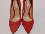 des chaussures à talons hauts rouges posées sur une surface blanche, avec un fond blanc