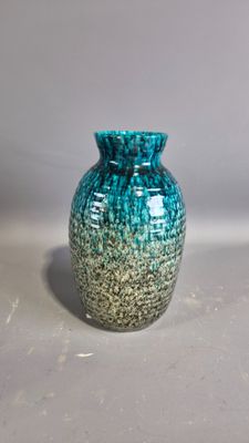 a blue and green vase sitting on a white surface