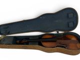 un vieil étui à violon contenant un violon, posé sur une surface blanche