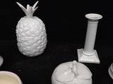 a lot of white candles and a pineapple on the table