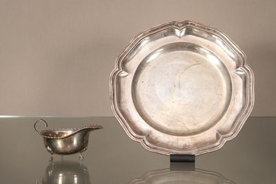 une assiette en argent posée sur une table en verre, à côté d'un bol en argent