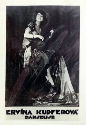 photographie en noir et blanc d'une femme assise sur une chaise, vêtue d'une robe