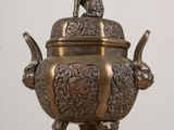 a bronze teapot on a wooden table with a cat on top