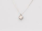 un pendentif en forme de diamant blanc suspendu à une chaîne, sur fond blanc
