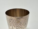 a silver cup sitting on a white surface