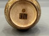 an image of a small vase with a gold decoration on it
