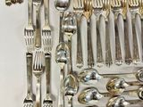a lot of silver spoons and forks laid out on a table
