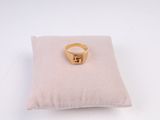 bague en or jaune posée sur un coussin, sur fond blanc