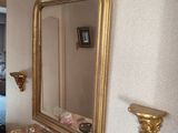 un miroir posé sur une commode, dans une chambre avec un lit en arrière-plan