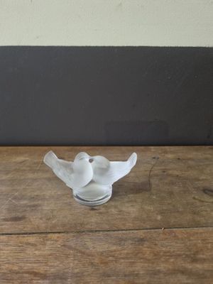 a small glass bird sitting on a wooden table