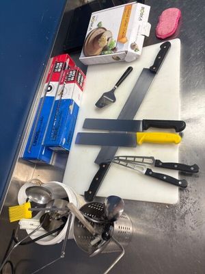 une planche à découper sur laquelle sont posés un couteau et d'autres ustensiles de cuisine