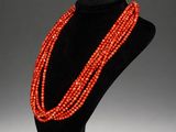 a red beaded necklace on a black mannequin stand
