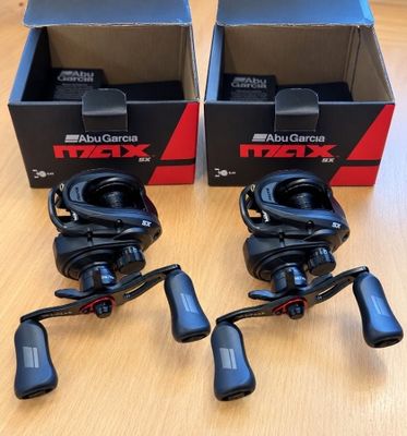 two boxes of fishing reels sitting on top of a wooden table