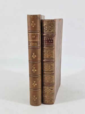 two old books sitting on top of each other on a white surface
