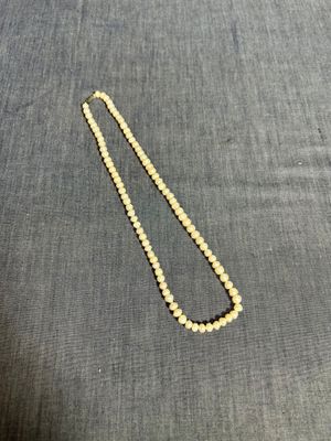 un gros plan d'un collier de perles posé sur un tissu bleu