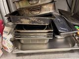 several pans and pans are stacked on a shelf in a kitchen
