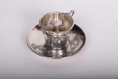 une tasse et une soucoupe en argent posées sur une soucoupe
