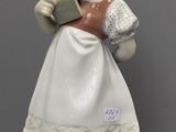 une figurine représentant une femme en train de lire un livre