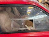 a teddy bear sitting in the passenger seat of a red car