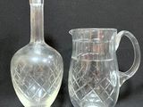 two clear glass vases and a glass pitcher on a black background