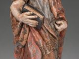 a wooden statue of a man holding a book in his hands