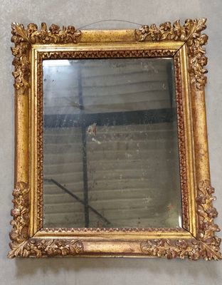 un miroir à cadre doré accroché au mur d'une pièce