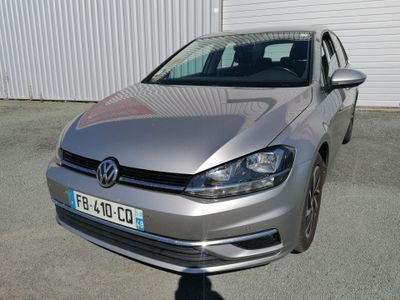 La Volkswagen Golf argentée est garée devant un immeuble.