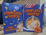 two boxes of cornflakes frosted cereal sitting on a table