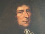 portrait of a man in a black coat with a white and gold tie