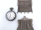 deux sacs à main et une montre de poche posés sur une surface blanche