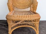 a wicker chair that is sitting against a white wall